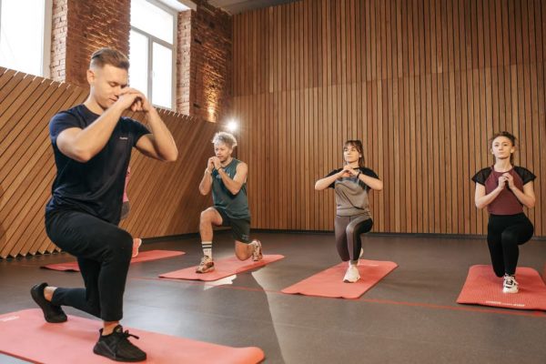 Adults practicing exercises on yoga mats in a contemporary studio setting.